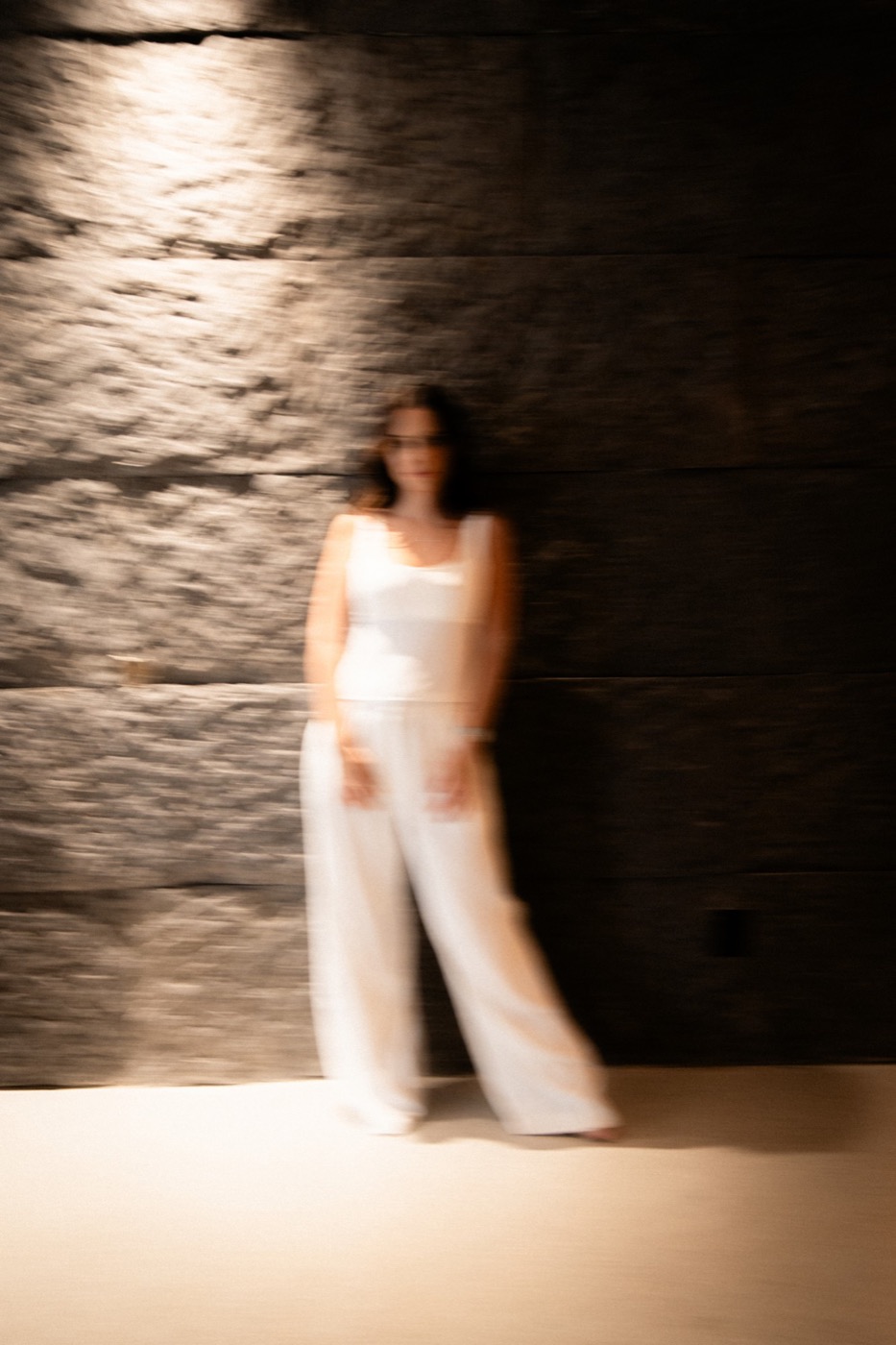 Dra. Alice Pastorini Pires de branco diante da parede de pedra, em foto com movimento