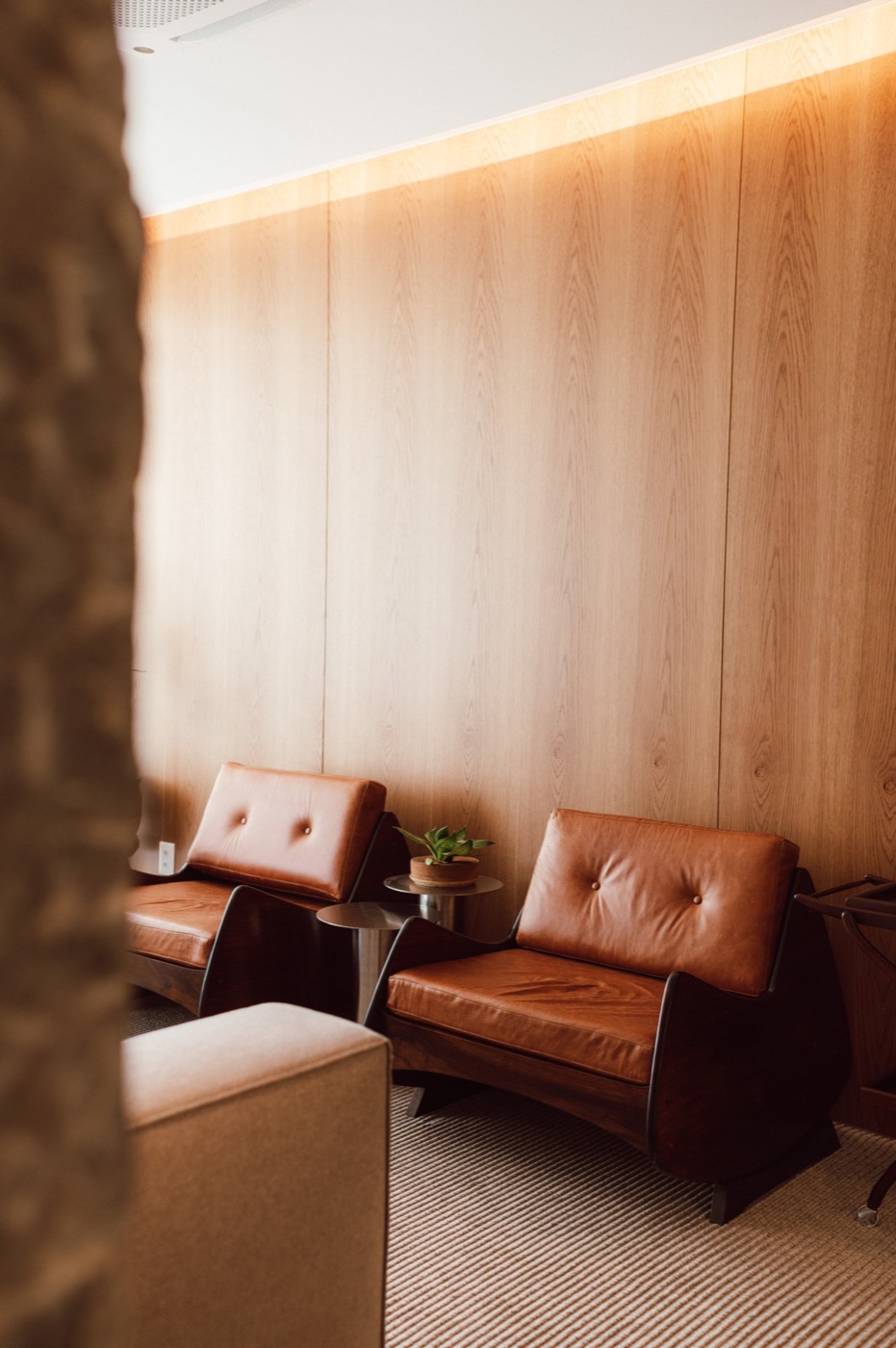 Sala de espera com poltronas de couro e parede de madeira